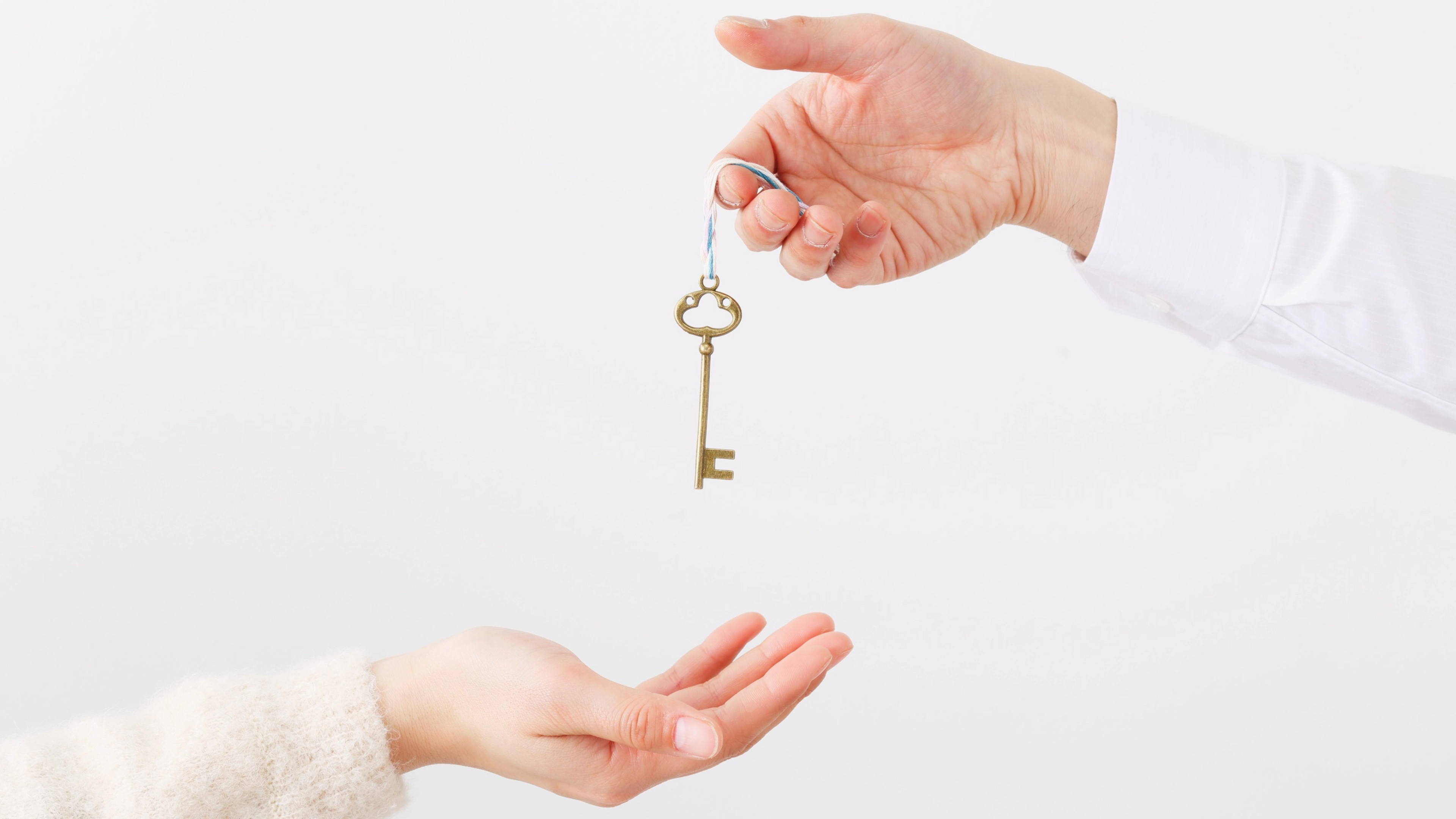 A hand holding a key, amount to give it to another hand.