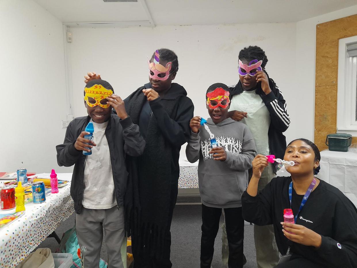 Children wearing masks they designed at the event, and blowing bubbles.