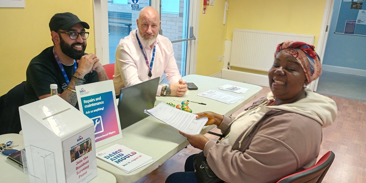 A resident is sitting at a table across from members of our repairs team giving her feedback.
