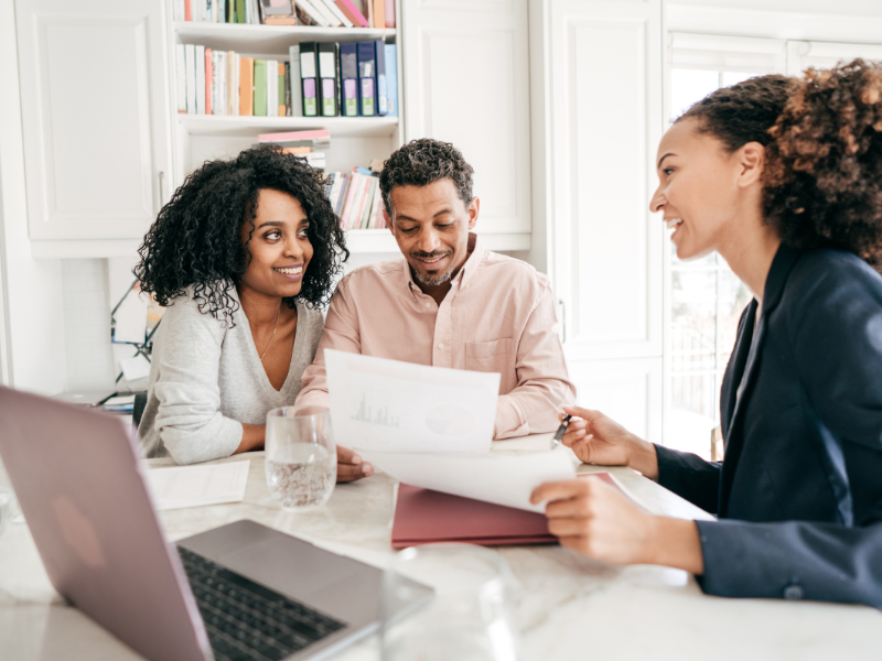 A couple go over documents with a professional looking woman. 