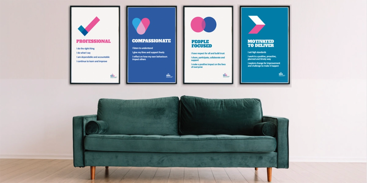 ISHA's four values as posters on the wall behind a teal sofa.