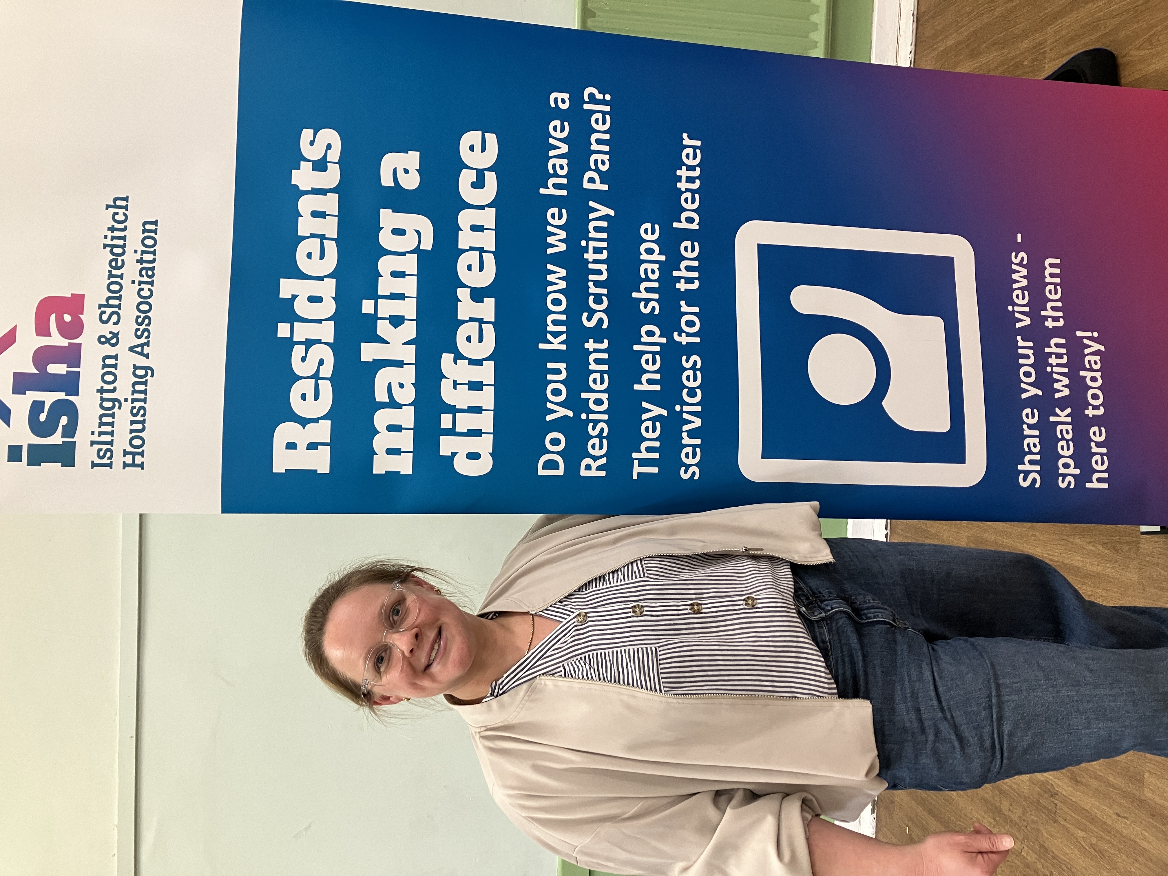Resident Scrutiny Panel member poses with a sign reading, "Residents making a difference". 