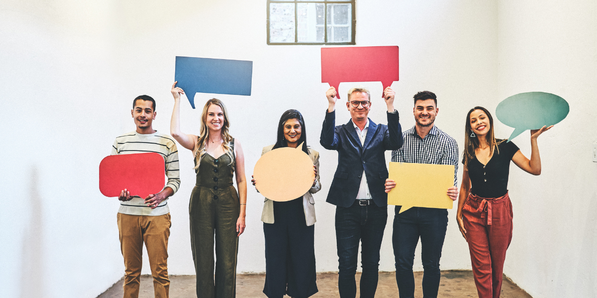 A diverse group of people hold cards shaped like speech bubbles. 